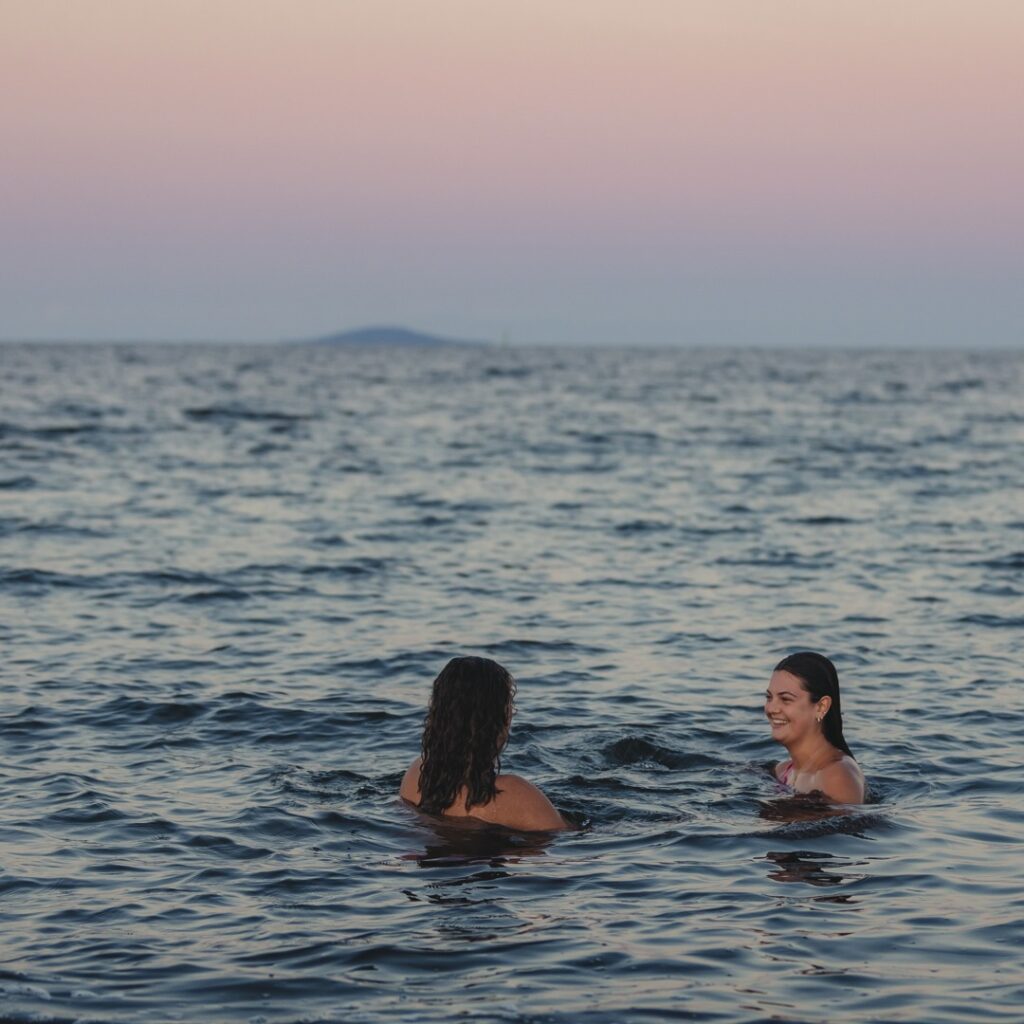 Ett par som badar med Blå jungfrun på horisonten.
